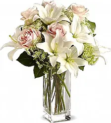 Roses with lilies or soft-toned lilies with mixed seasonal decorative greenery and matching packaging